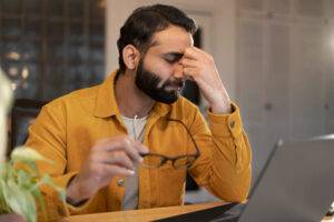 Empreendedor frustrado tentando montar sua loja virtual sozinho, diante do computador
